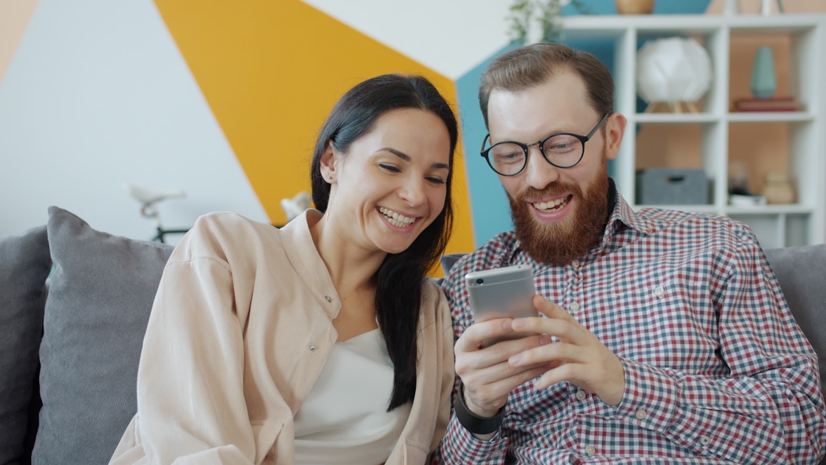 Couple laughing together while looking at a phone