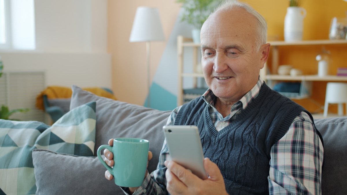 Man relaxing at home with phone and coffee