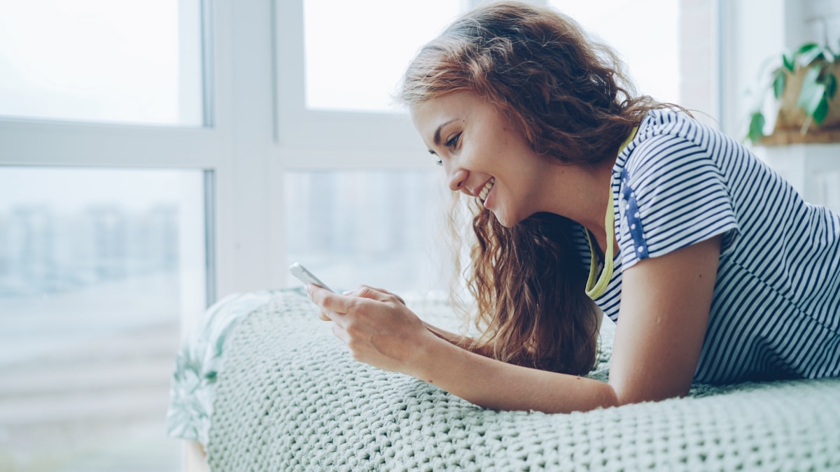 Woman smiling while looking at her phone
